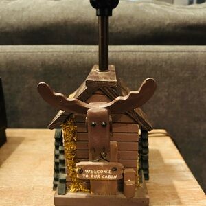 cabin themed tabletop lamp with a moose head & Welcome to Our Cabin" sign.